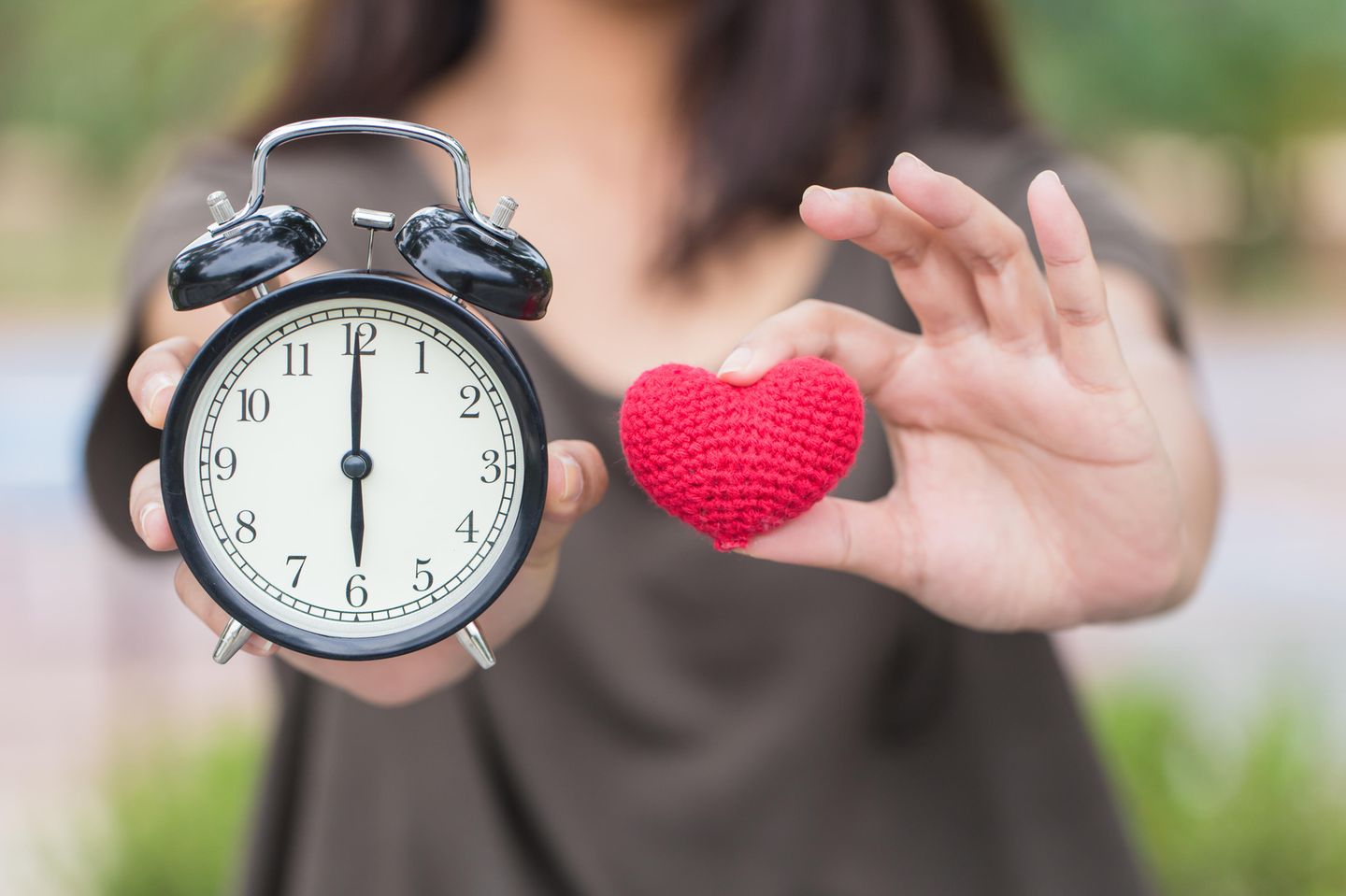 Zeit schenken: Frau mit Herz und Uhr in den Händen