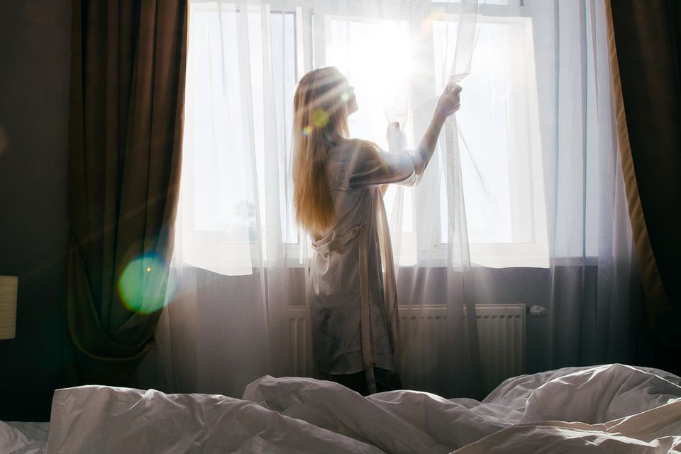 Ist das Hotelzimmer sauber: Frau schiebt Vorhänge zur Seite
