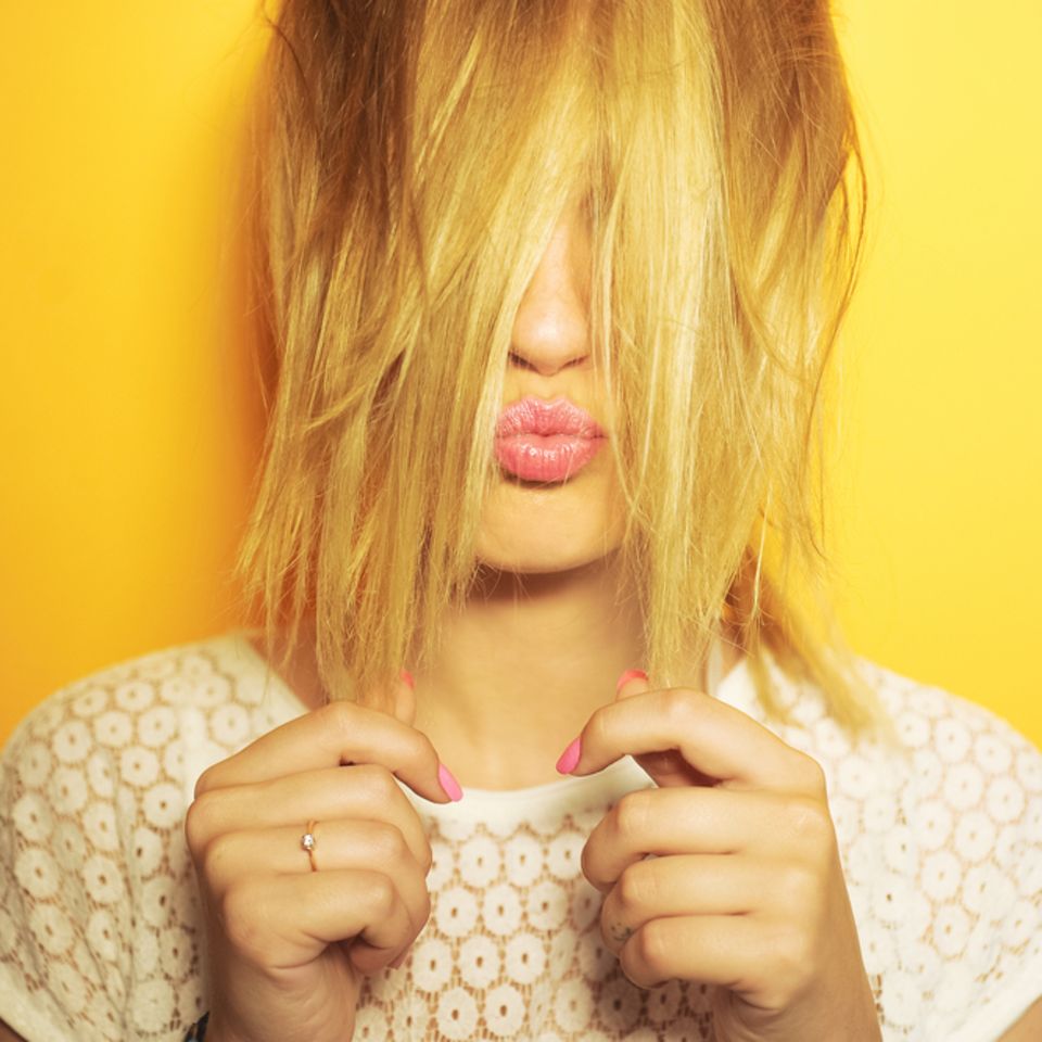 Gelbstich im Blond: Frau mit gelben Haaren macht Kussmund