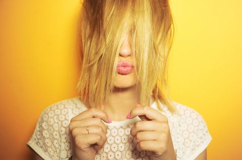 Gelbstich im Blond: Frau mit gelben Haaren macht Kussmund