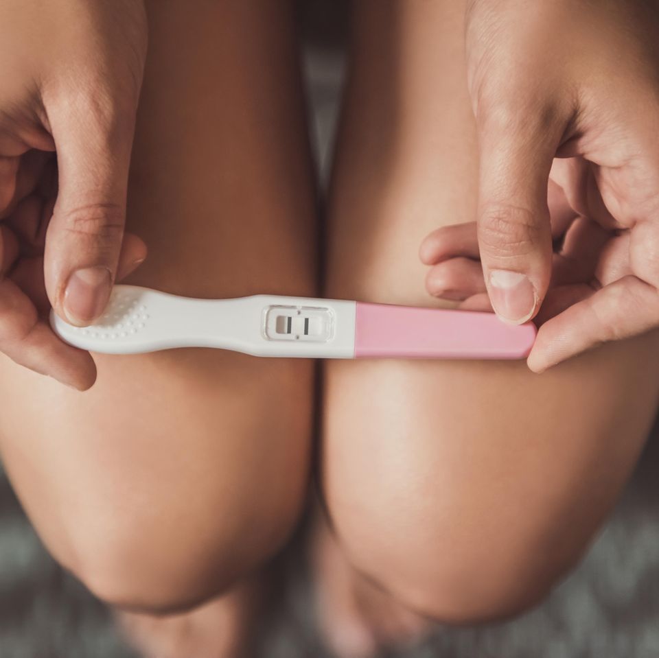 Schwangerschaftsfrühtest: Frauenbeine mit Schwangerschaftstest
