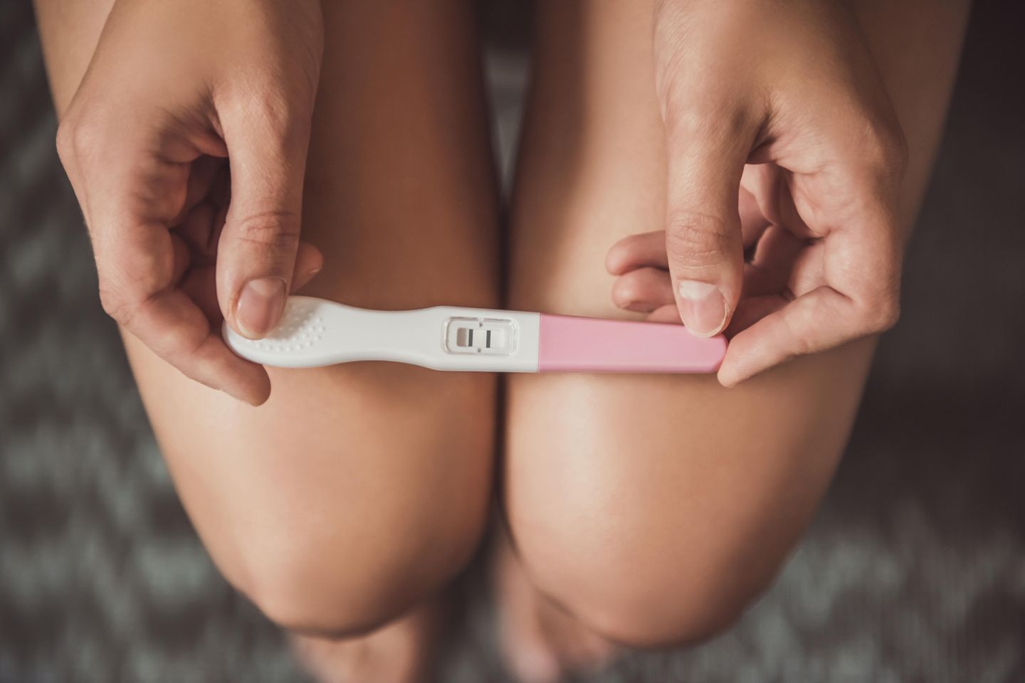 Schwangerschaftsfrühtest: Frauenbeine mit Schwangerschaftstest