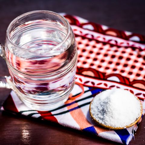 Hausmittel gegen Sodbrennen:Glas Wasser auf einem bunten Tuch, daneben eine Schale mit hellem Pulver