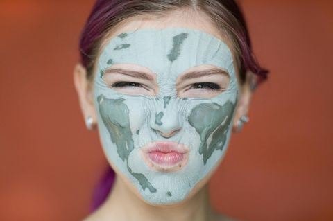 Skin Gritting: Frau mit Maske aus Tonerde im Gesicht