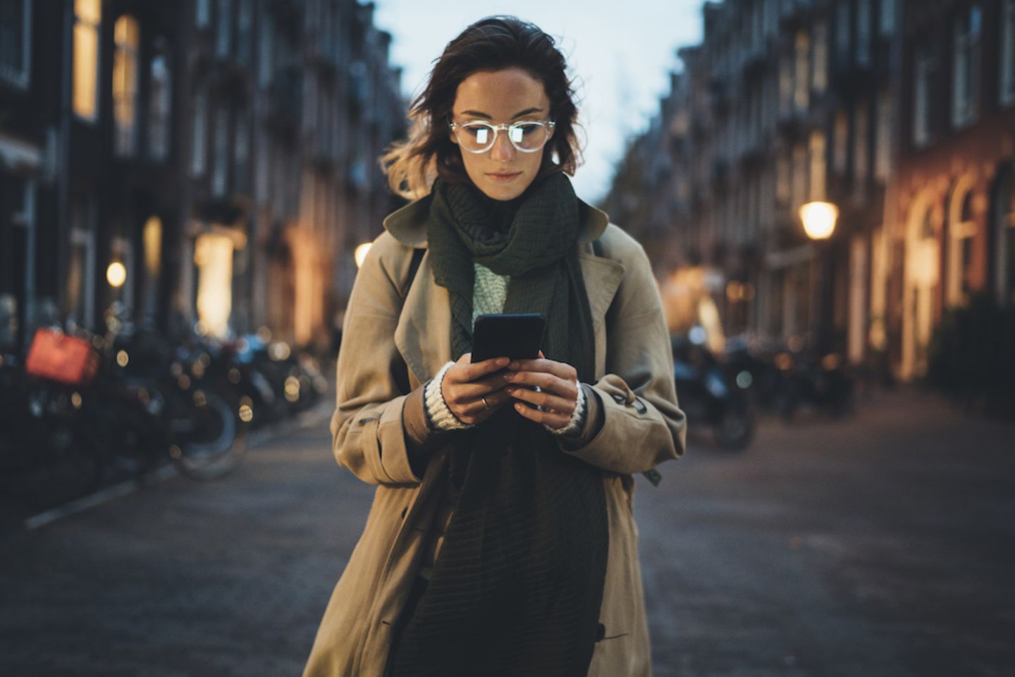 Digitale Abhängigkeit: Frau steht auf einer Straße und schaut auf ihr Handy