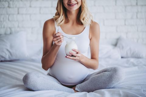 Ernährung in der Schwangerschaft: Schwangere ist Joghurt im Bett