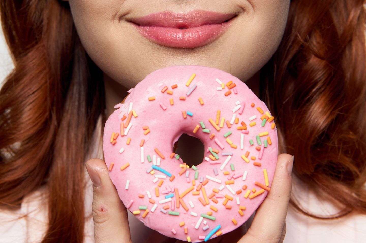 Ernährungsfalle: Frau hält Donut vor ihr Gesicht