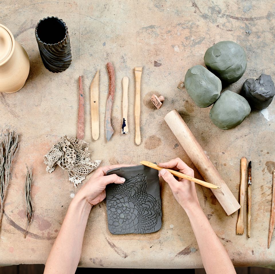 Töpfern: Ideen für selbst gemachte Keramik: Tonkugeln, Schaber auf dem Tisch. Hände verzieren Ton