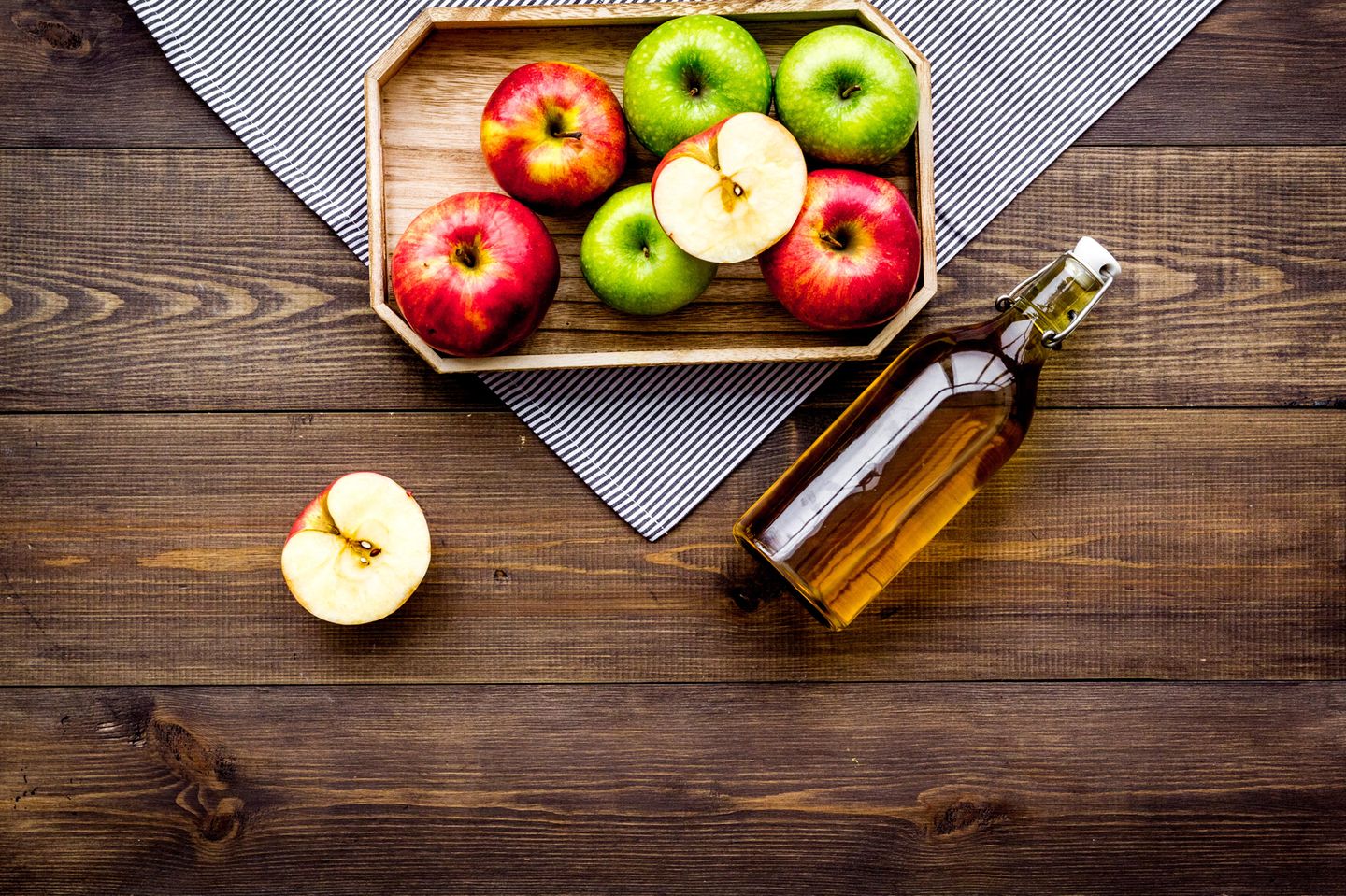 Apfelessig Haare: Tablett mit Äpfeln auf dem Tisch und einer Flasche Apfelessig