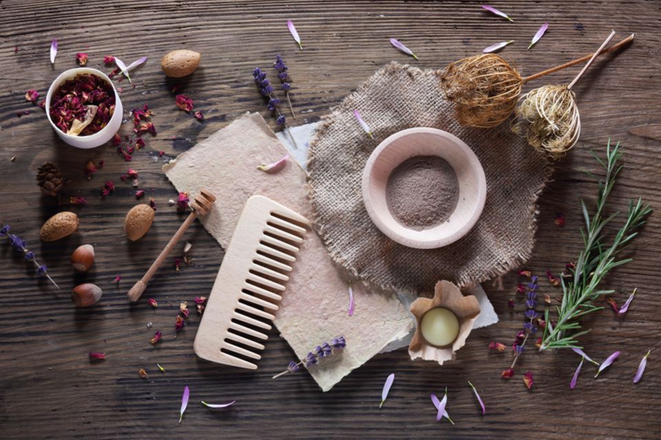 Shampoo selber machen - Rezepte und Anleitung: Kamm, Schüssel mit Pulver und Rosmarinzweige liegen auf einem Holztisch