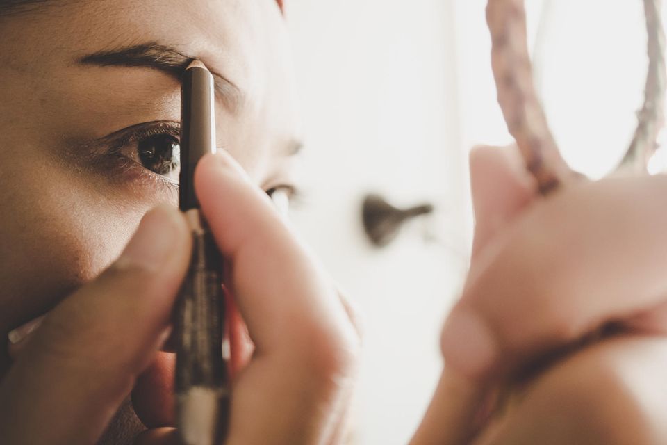 Bleached Brows: Frau, die sich die Augenbrauen anmalt