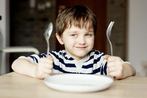 Tipps, wie Kinder Warten lernen: Junge wartet brav vor leerem Teller auf sein Essen