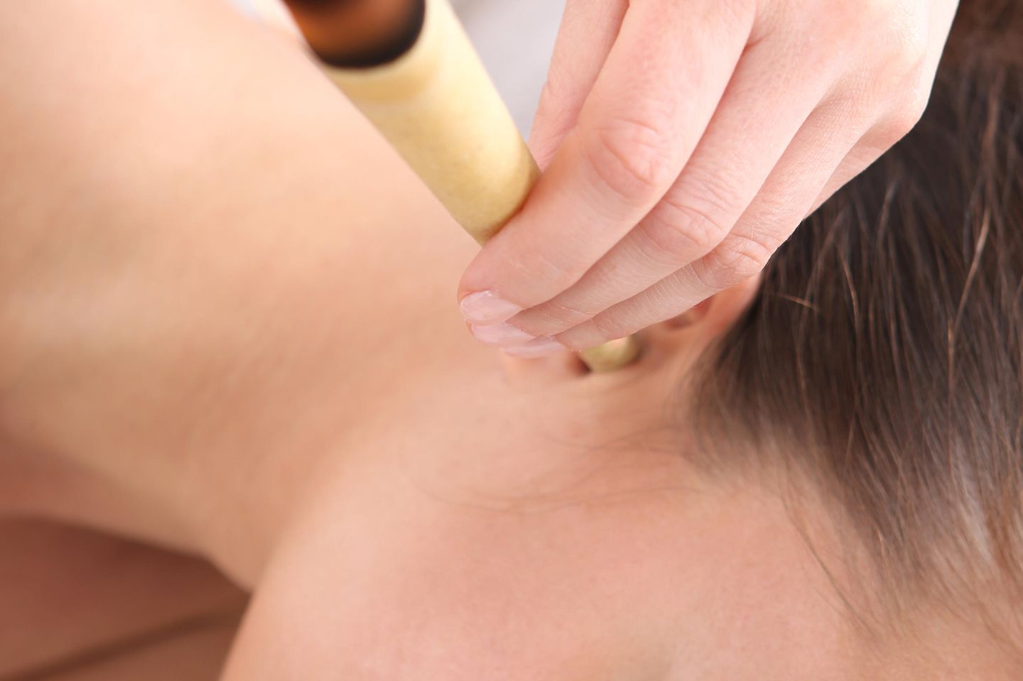 Ohrenkerzen Anwendung: Frau hält Ohrenkerze ins Ohr