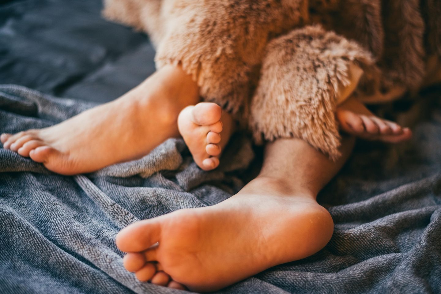 Sexsomnia: Zwei ineinander verschränkte Fußpaare schauen unter der Bettdecke hervor