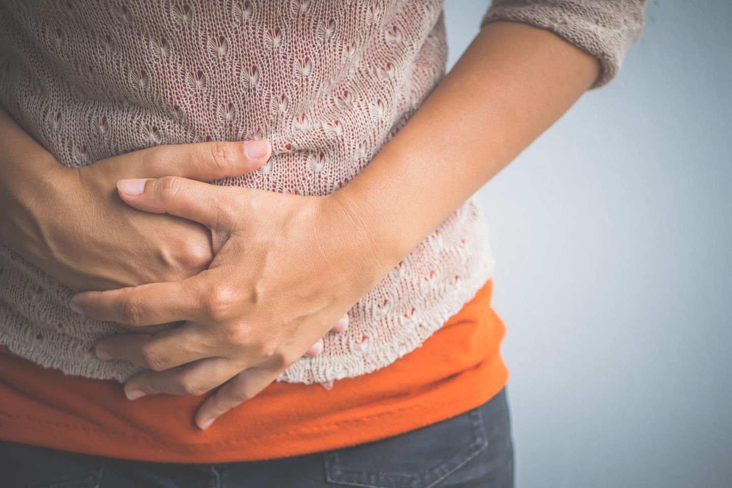 Bauchnabel entzündet: Frau hält sich mit Händen den Bauch