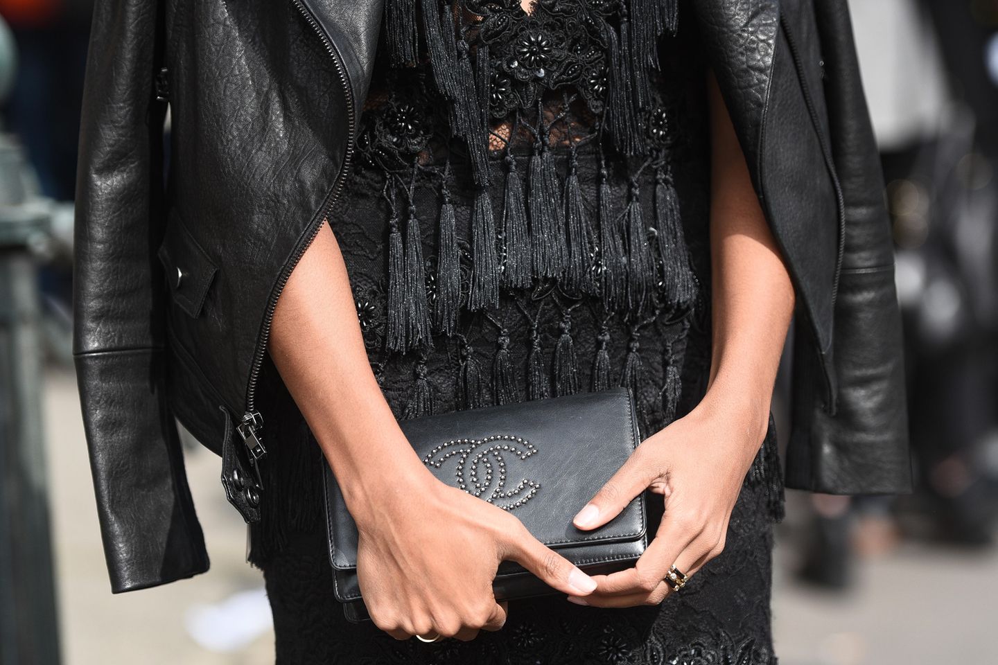 Silvester-Outfit Inspiration: Frau mit schwarzer Handtasche in den Händen und Lederjacke