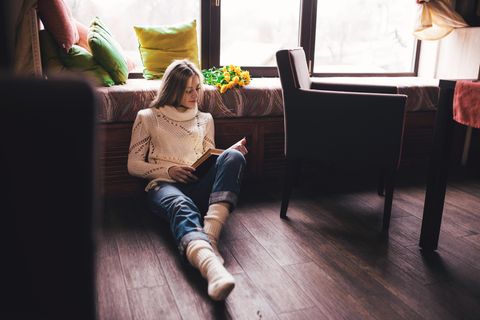 Single-Gen: Eine junge Frau sitzt allein auf dem Boden und liest ein Buch