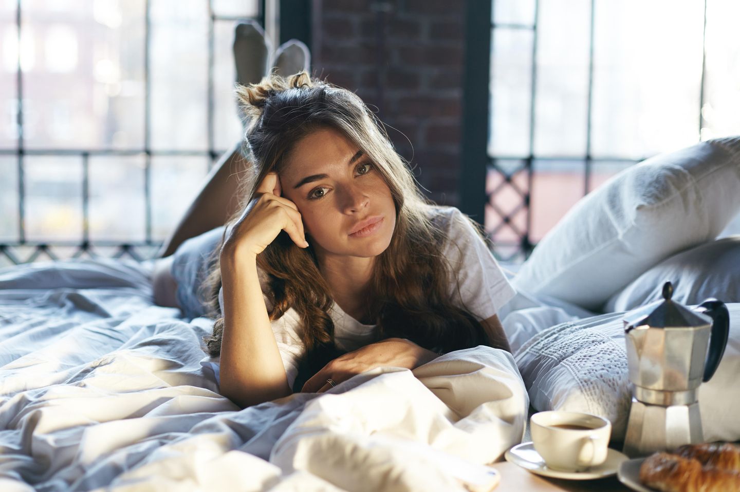 Was tun gegen Langeweile – 13 Tipps gegen öde Tage: Frau liegt auf dem Bett, Kopf auf den Arm gestützt und schaut gelangweil