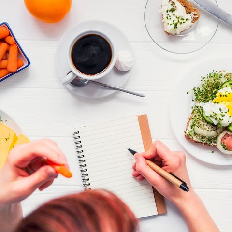 Ernährungsplan erstellen: Frau mit Notizblock am Küchentisch