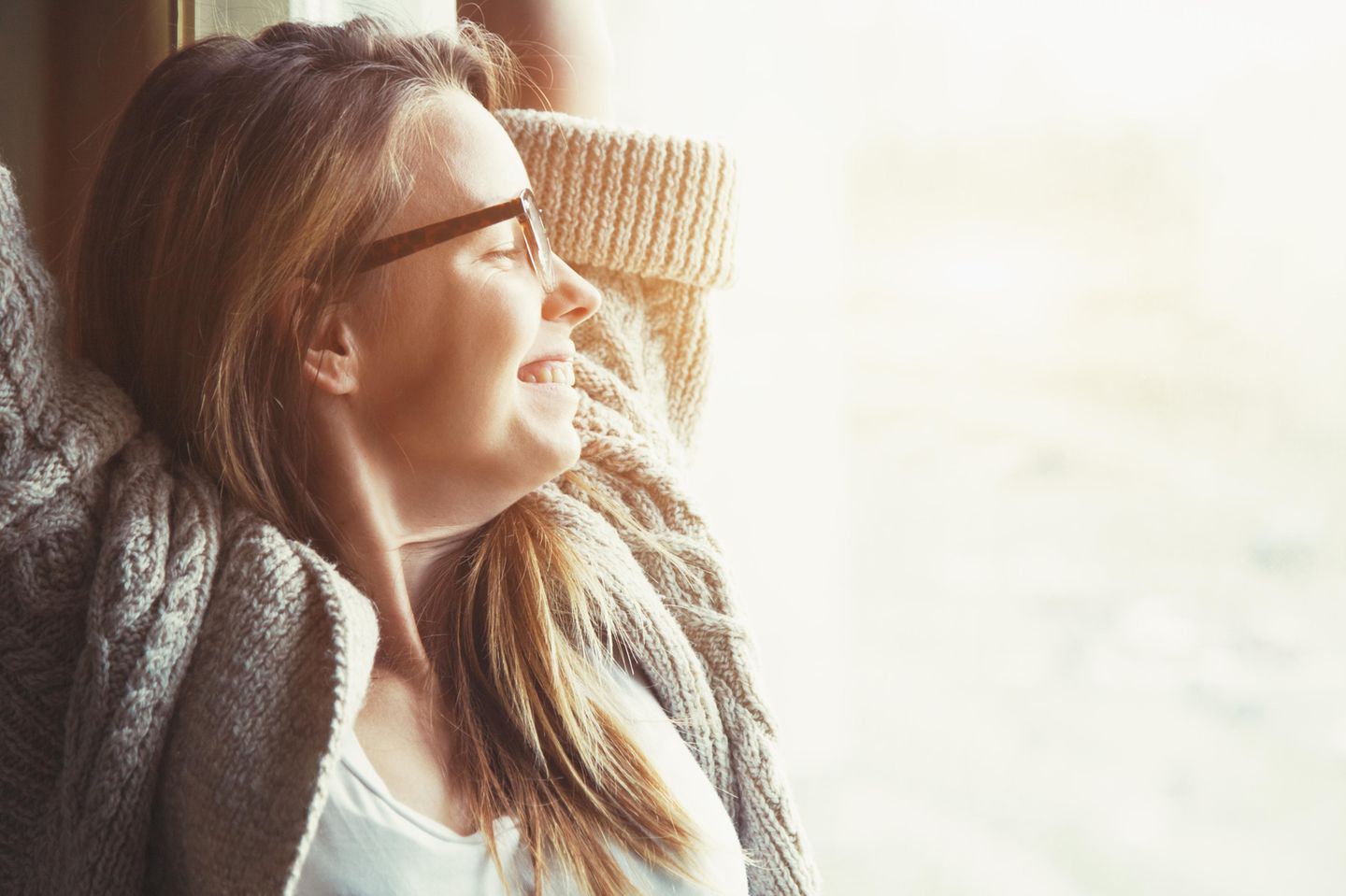 Einfache Tricks, um glücklich zu sein: Eine zufriedene junge Frau lehnt sich entspannt zurück