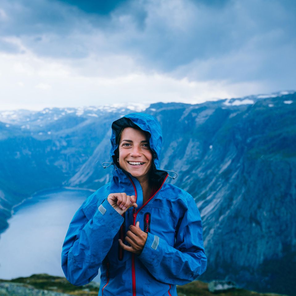Regenjacke imprägnieren – mit diesen Tipps klappt's! Frau steht in Regenjacke vor einer Berglandschaft