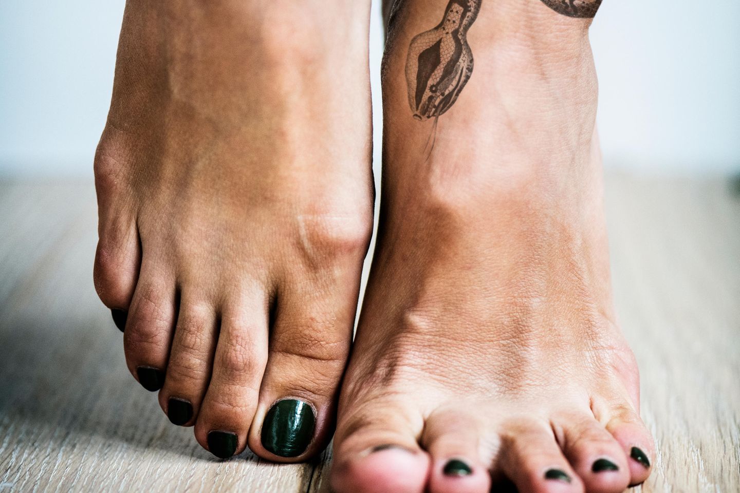 Tattoo am Fuß: Zwei Frauenfüße mit Schlangentattoo