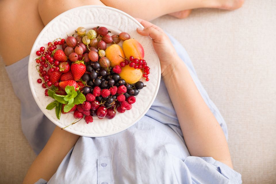 Fructoseintoleranz: Was darf ich essen? Frau hält einen Teller mit verschiedenen Obstsorten in der Hand