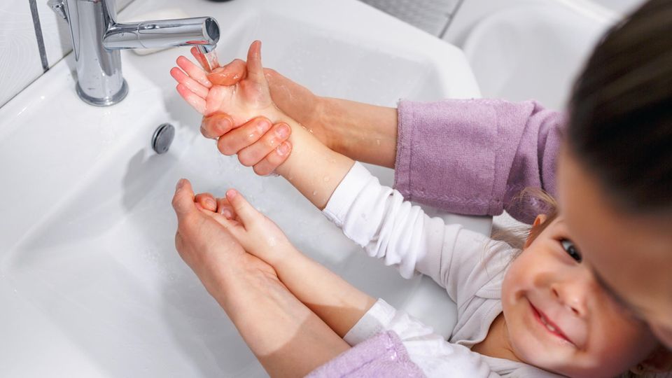 Erkältung: Mutter wäscht mit Kind die Hände