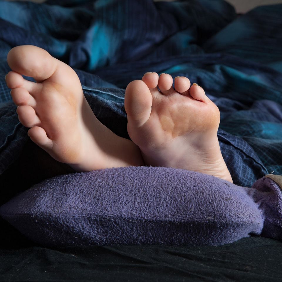 Tipps bei Kälte: Füße im Bett auf einer Wärmflasche