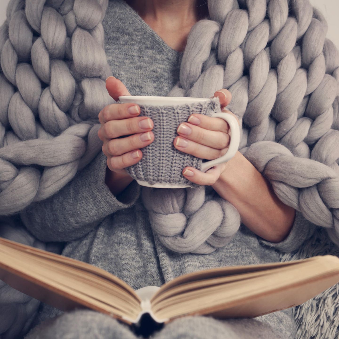 Tipps bei Kälte: Frau auf der Couch mit Decke um die Schultern