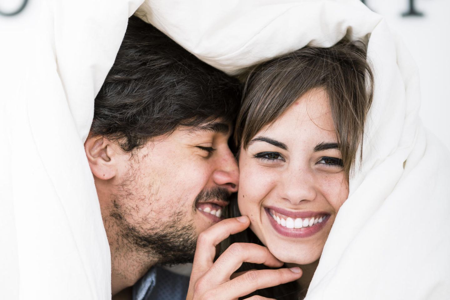Was ist das Geheimnis glücklicher Beziehungen? Ein glückliches Paar unter einer Bettdecke