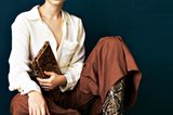 Reptilienprint: Frau in cremefarbener Bluse, brauner Stoffhose und Stiefel mit Schlangenprint