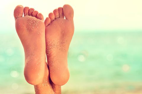 Fußpeeling: Zwei Füße am Meer mit Sand auf der Fußsohle