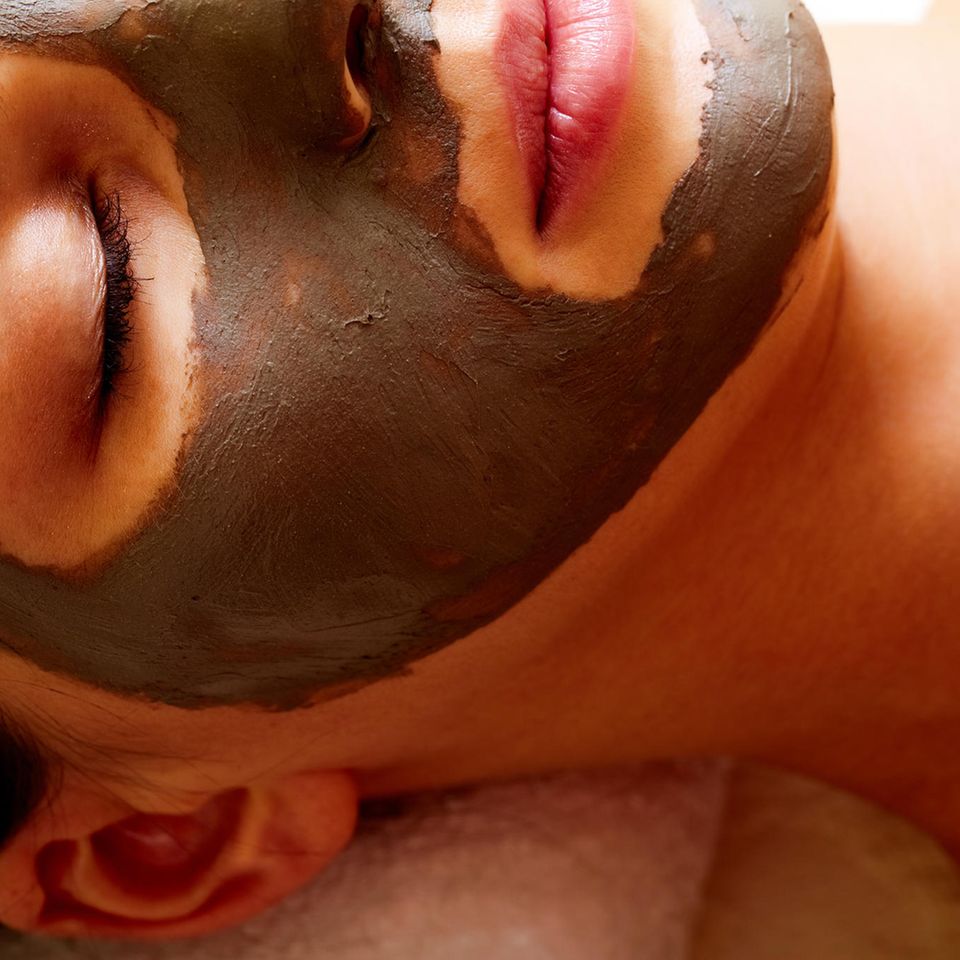 Poren reinigen: Frau mit Maske aus Heilerde im Gesicht