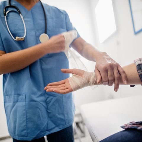 Krankenschwester Gehalt: Krankenschwester verbindet Hand eines Patienten