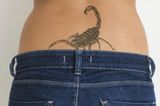 Tattoo Motive: Eine Frau mit einem Skorpion-Tattoo am Steißbein
