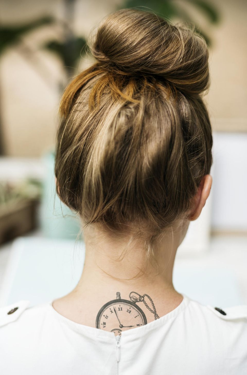 Tattoo Motive: Eine Frau mit einem Taschenuhr-Tattoo am oberen Rücken