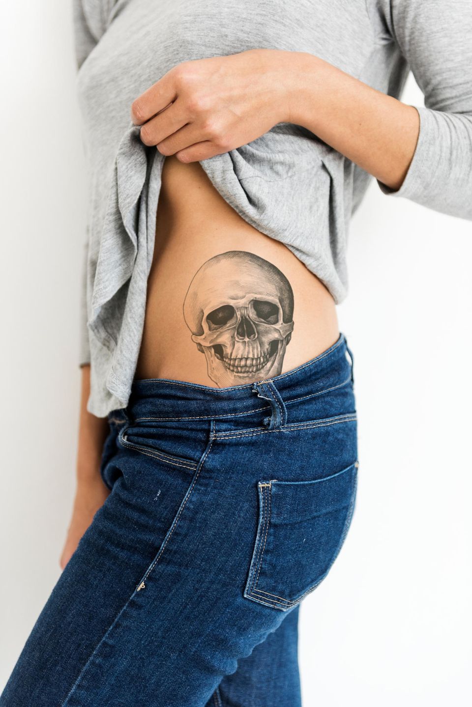 Tattoo Motive: Eine Frau mit einem Totenkopf-Tattoo auf der Hüfte