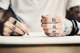 Tattoo Motive: Eine Frau mit Symbol-Tattoos auf den Fingern