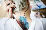 Tattoo Motive: Eine Frau mit Noten-Tattoo am Hals