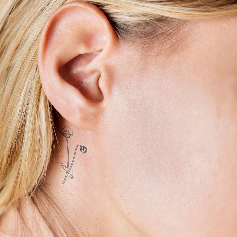 Tattoo Motive: Eine Frau mit einem sehr feinen Blumen-Tattoo am Ohr