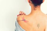 Tattoo Motive: Eine Frau mit einem Libellen-Tattoo auf der Schulter