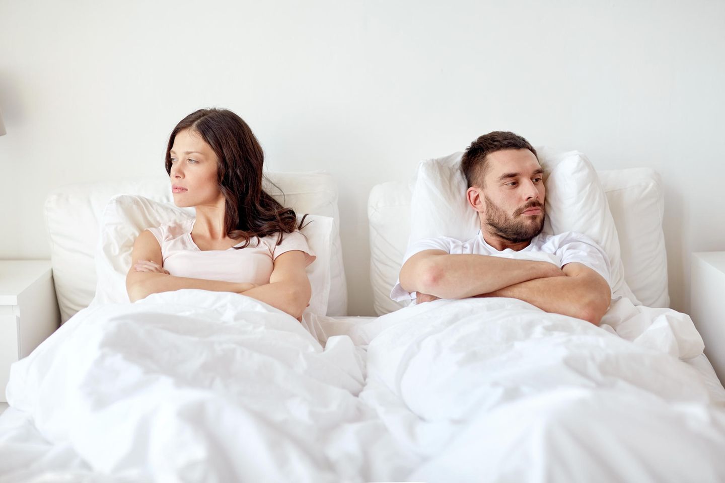 Das Hauptproblem in Beziehungen: Ein Paar liegt beleidigt und voneinander abgewandt im Bett