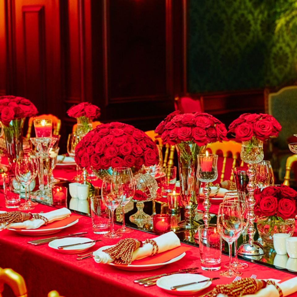 Rubinhochzeit: Bedeutung, Deko und Geschenkideen: Feierlich gedeckte Tafel in rot mit roten Blumensträußen