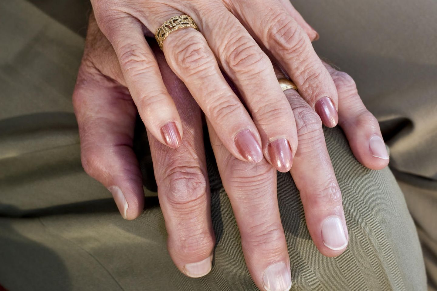 Goldene Hochzeit: Eine alte Frauenhand mit Ehering auf einer Männerhand