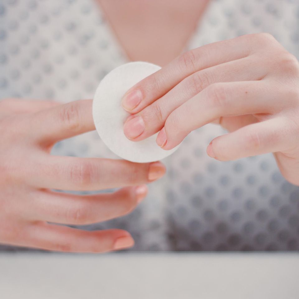 Acrylnägel entfernen: Zwei Hände, die mit Wattepad Nagellack entfernen