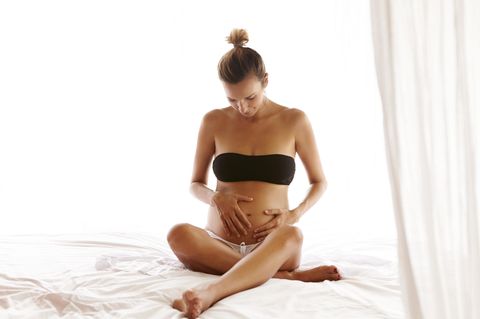 Dammmassage: Schwangere sitzt auf Bett