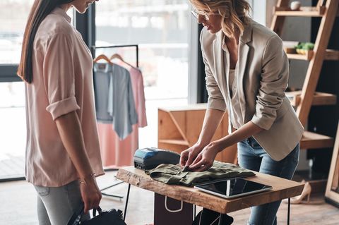 Einzelhandelskauffrau Gehalt: Verkäuferin in Modegeschäft kümmert sich um Kundin