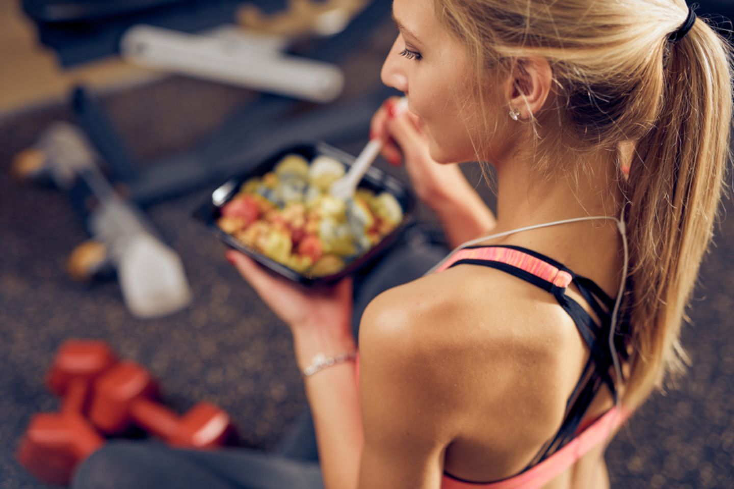 Essen nach dem Sport: Was du wirklich essen und was du vermeiden solltest: Frau in Sportkleidung hält Schale mit Essen