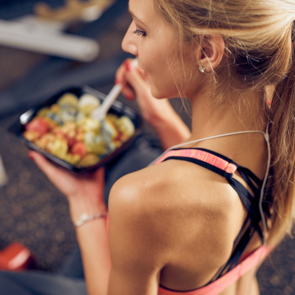 Essen nach dem Sport: Was du wirklich essen und was du vermeiden solltest: Frau in Sportkleidung hält Schale mit Essen